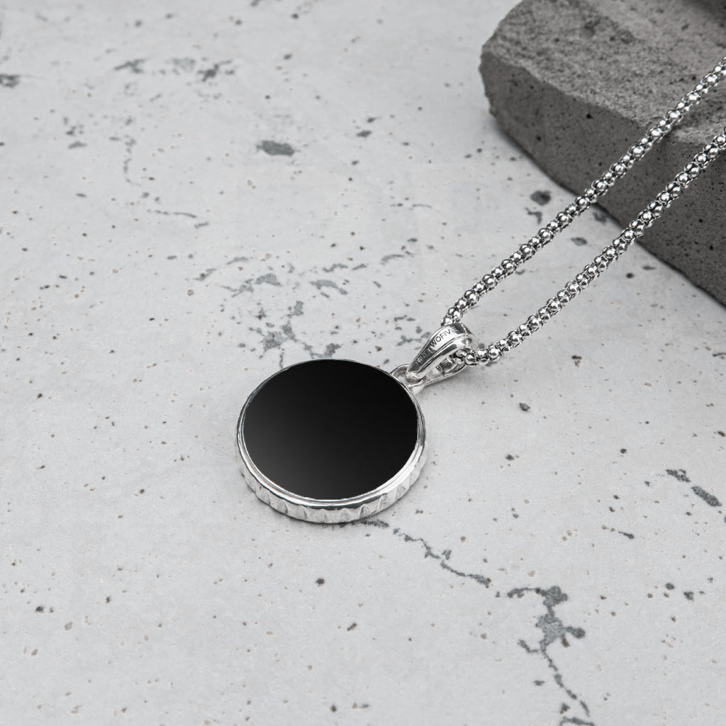 A black circle pendant on a silver chain, perfect for a man.