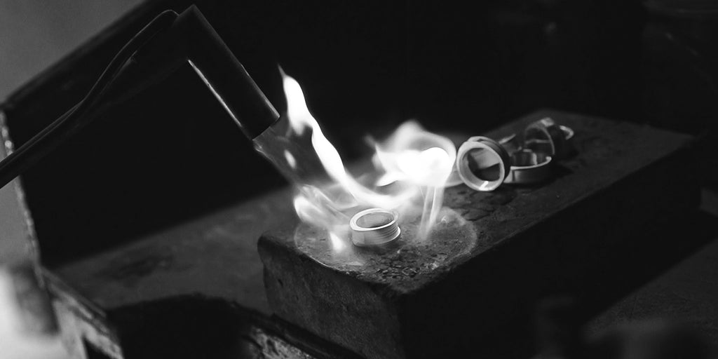 A black and white photo of a ring being made with a torch.