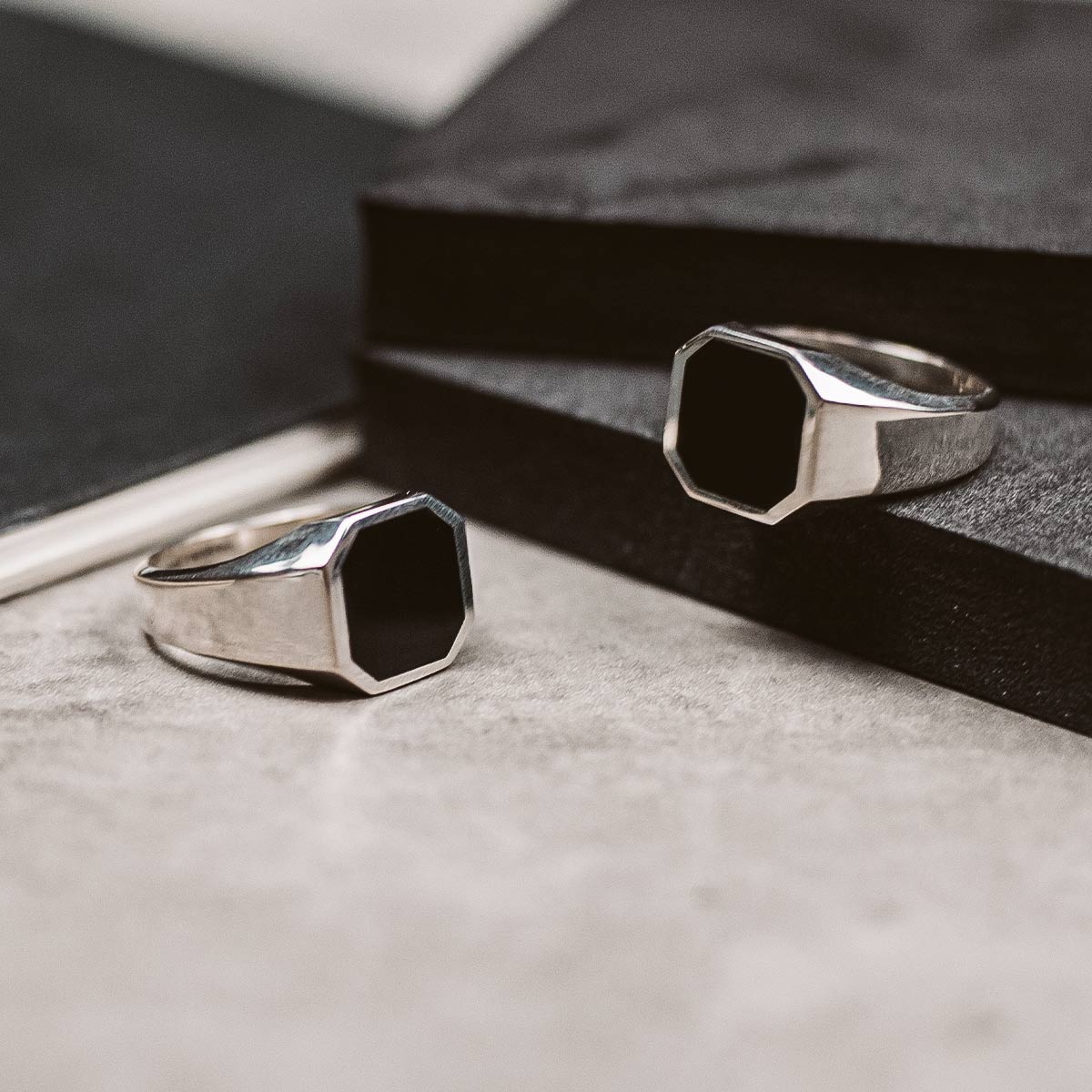 A pair of black onyx signet rings on top of a book.