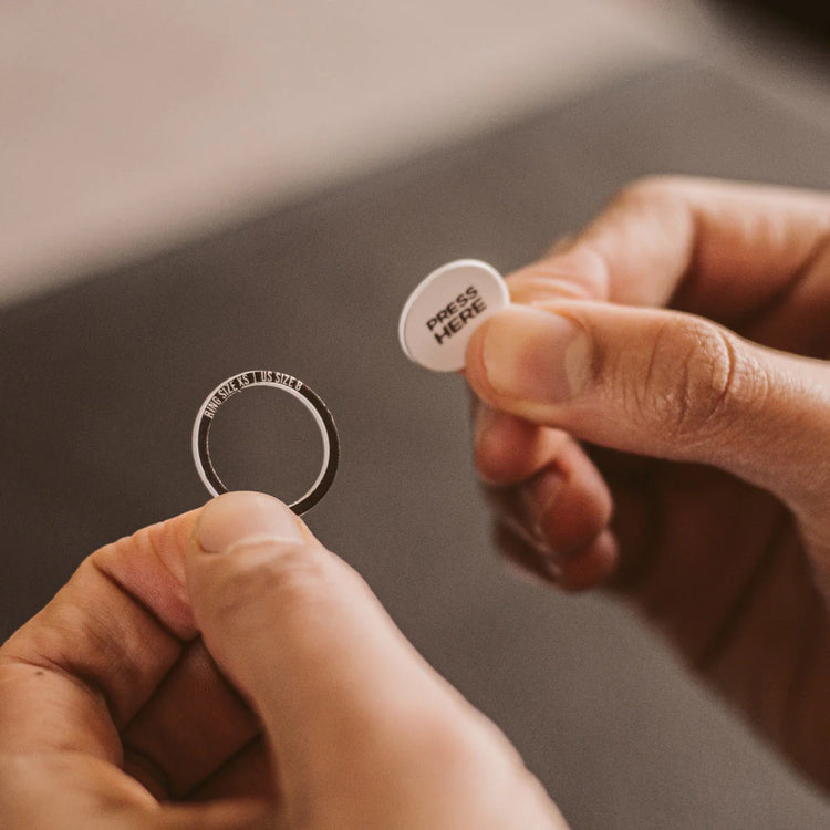 A person holding a ring with a small tag on it.