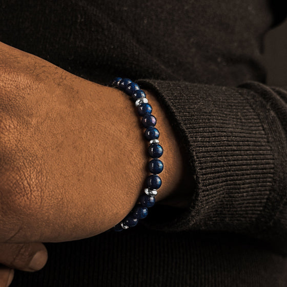 Der Mann im schwarzen Pullover trägt ein blau-silbernes Kadar-Perlenarmband für Herren von Ninetwofive.