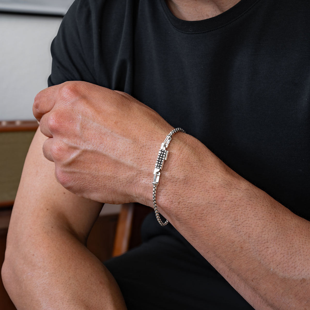 Homme portant une médaille d'argent boîte bracelet en chaîne sur un bras avec un arrière-plan flou