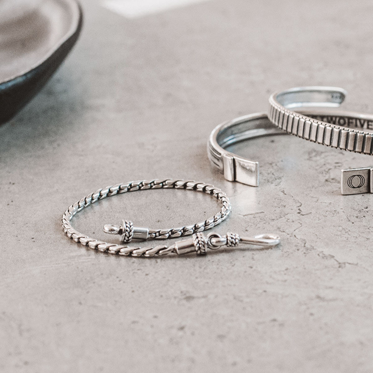 Een paar zilveren armbanden op een tafel.