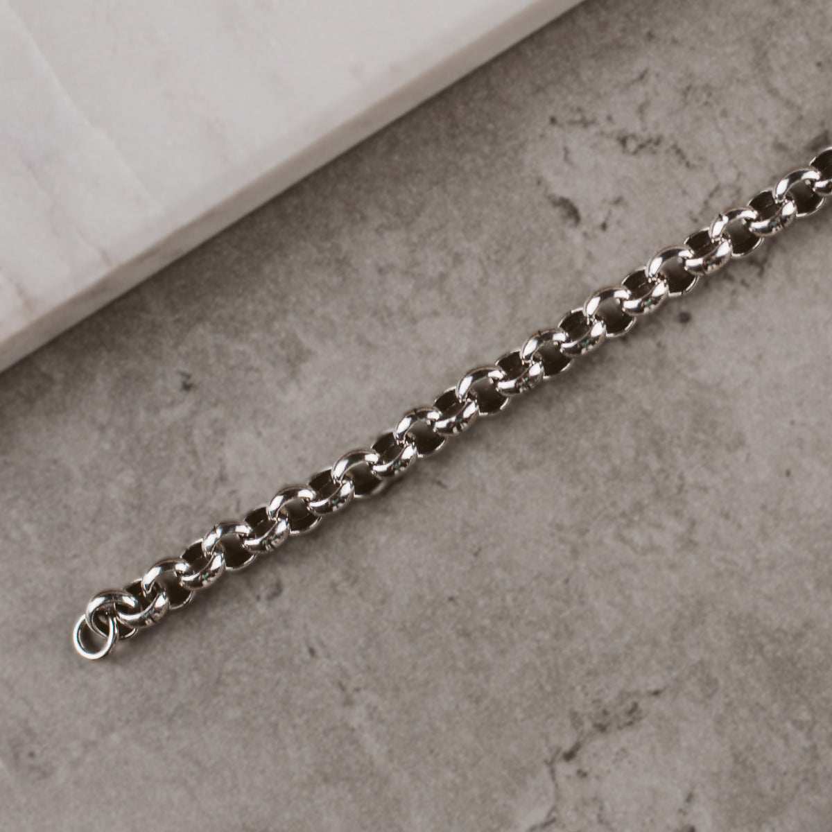 Un bracelet en chaîne en argent posé sur une bille.