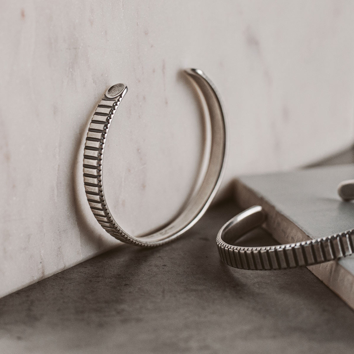 Ein Paar silberne Manschettenarmbänder auf einem Tisch.