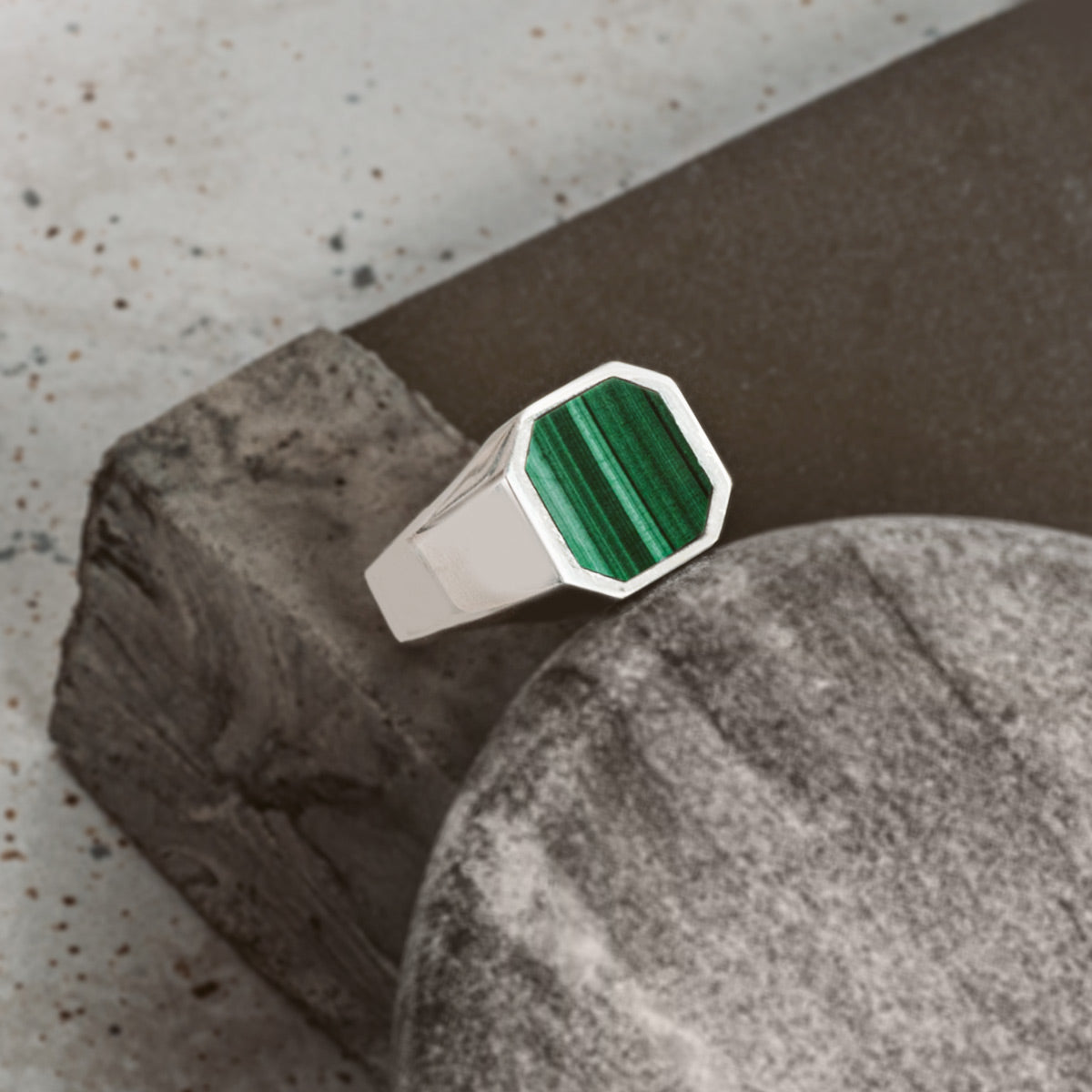 A ring with a green stone on top of a rock.