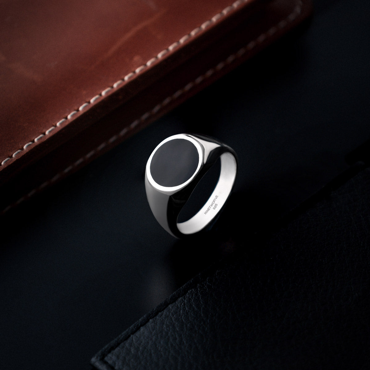 Adil sterling silver black onyx men’s signet ring from Ninetwofive with a brown wallet.