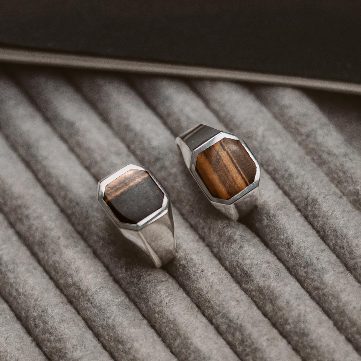 A pair of tiger eye signet rings on a background.