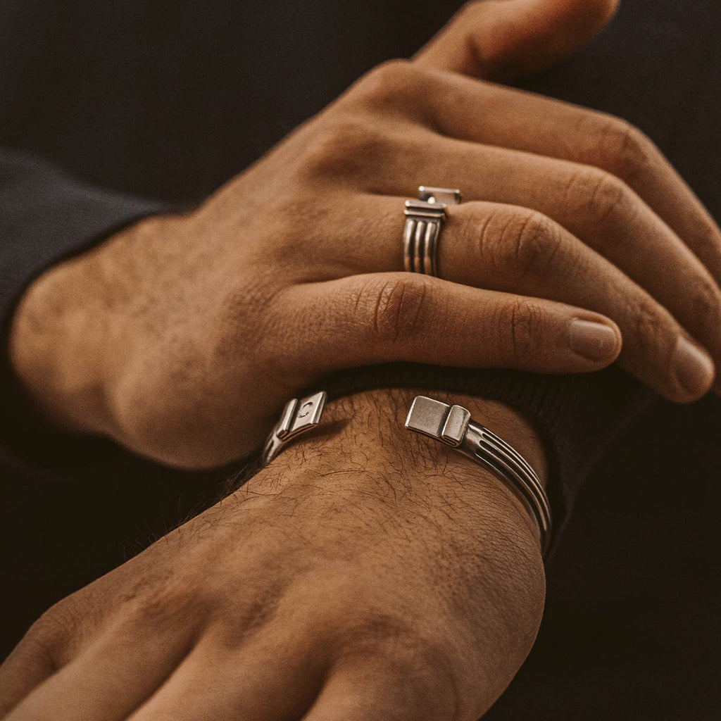 A man wearing a pair of silver cuff bracelets.