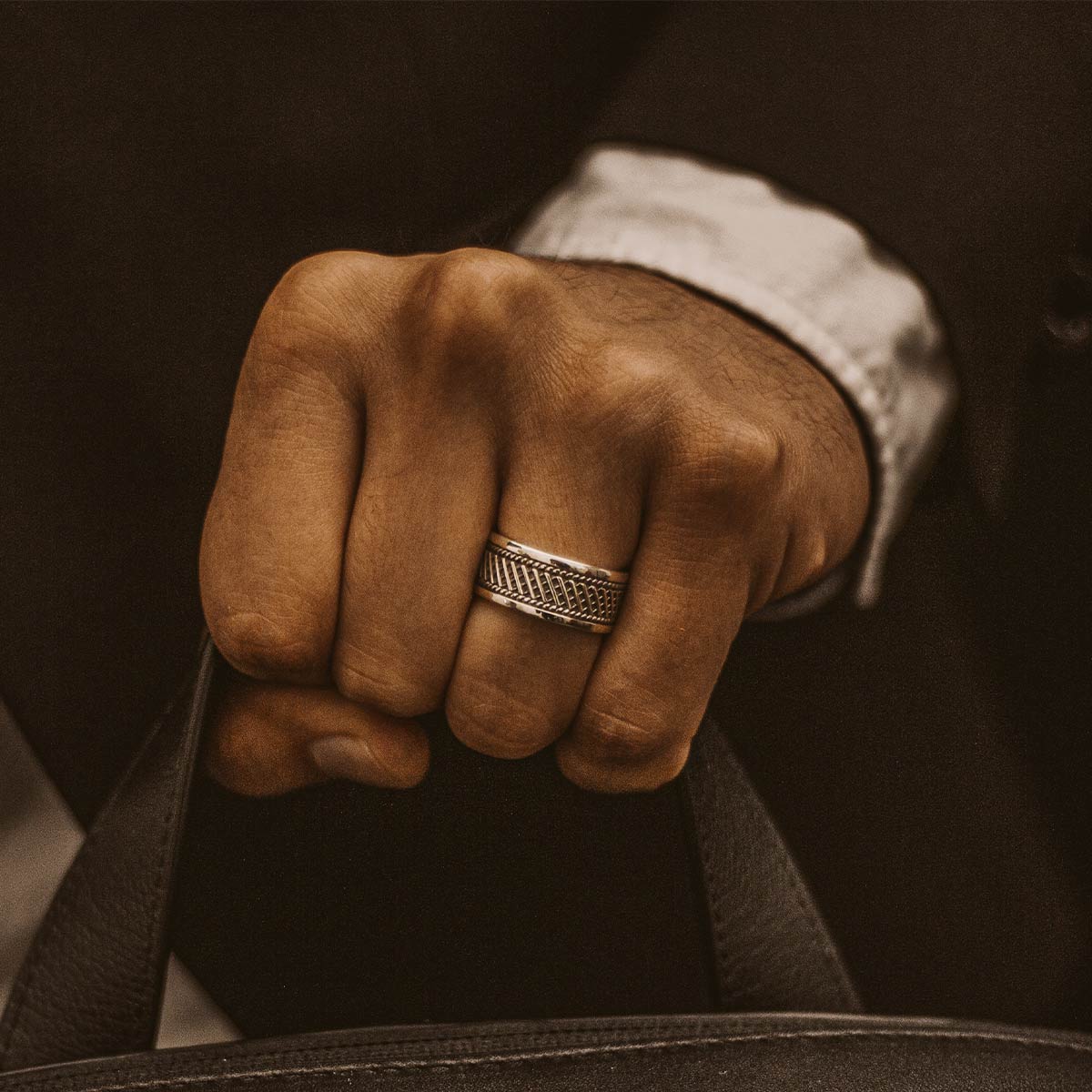 Un homme portant une bague Kaliq - Oxidized Sterling Silver Ring 10mm et tenant une mallette.