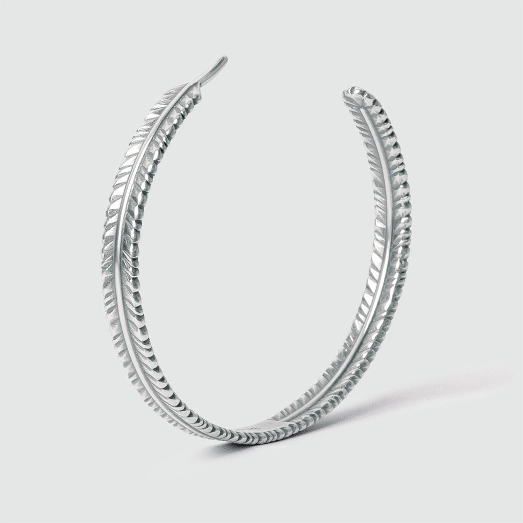 A Zahir - Thin Sterling Silver Feather Bangle 6mm earring with a feather design.