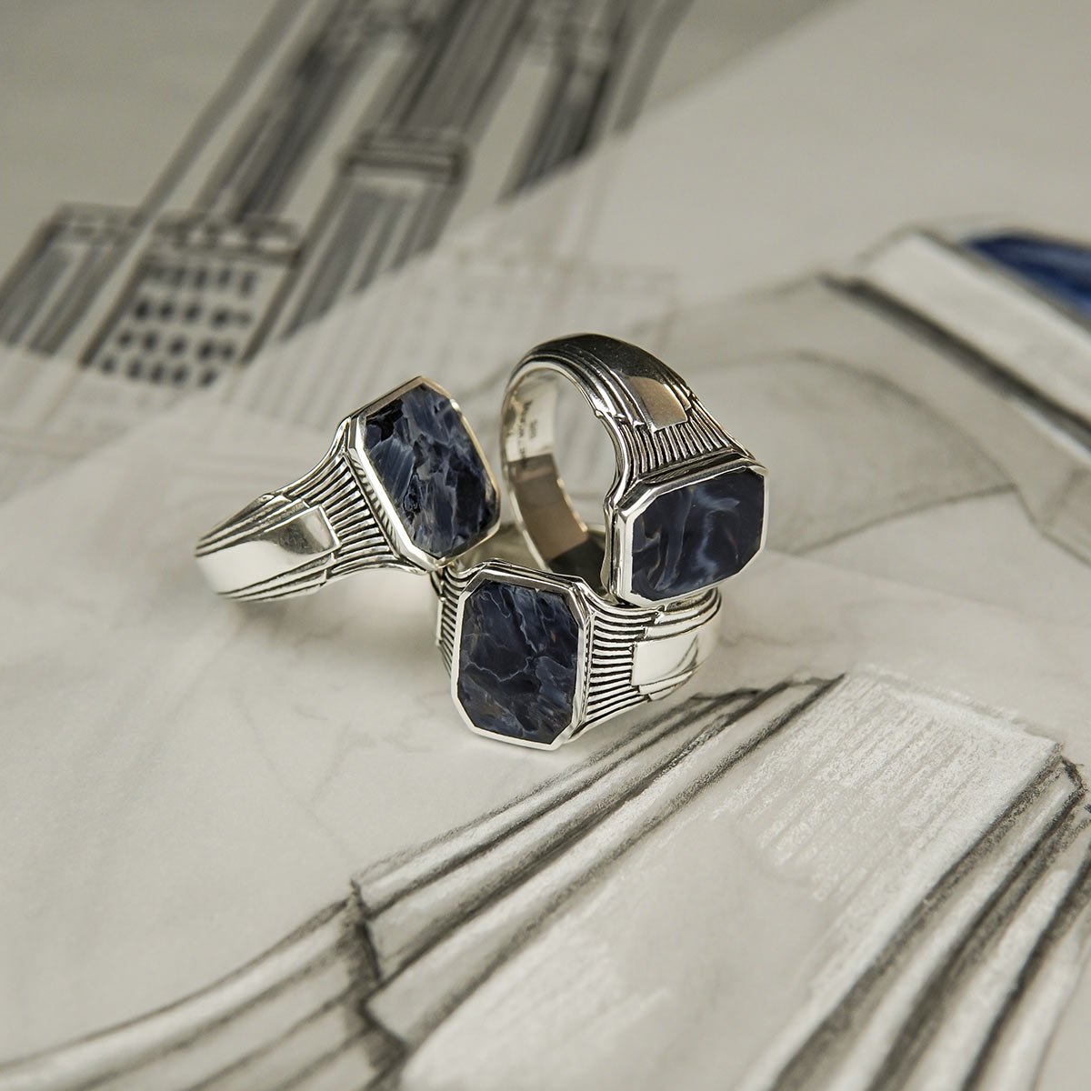 Pietersite mens ring placed on sketched design papers