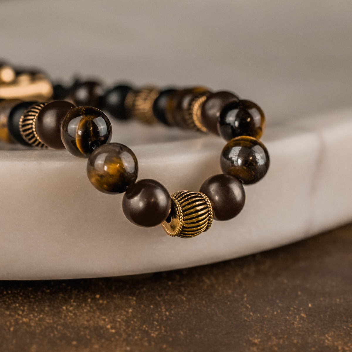 A tiger eye beaded bracelet on a marble slab.