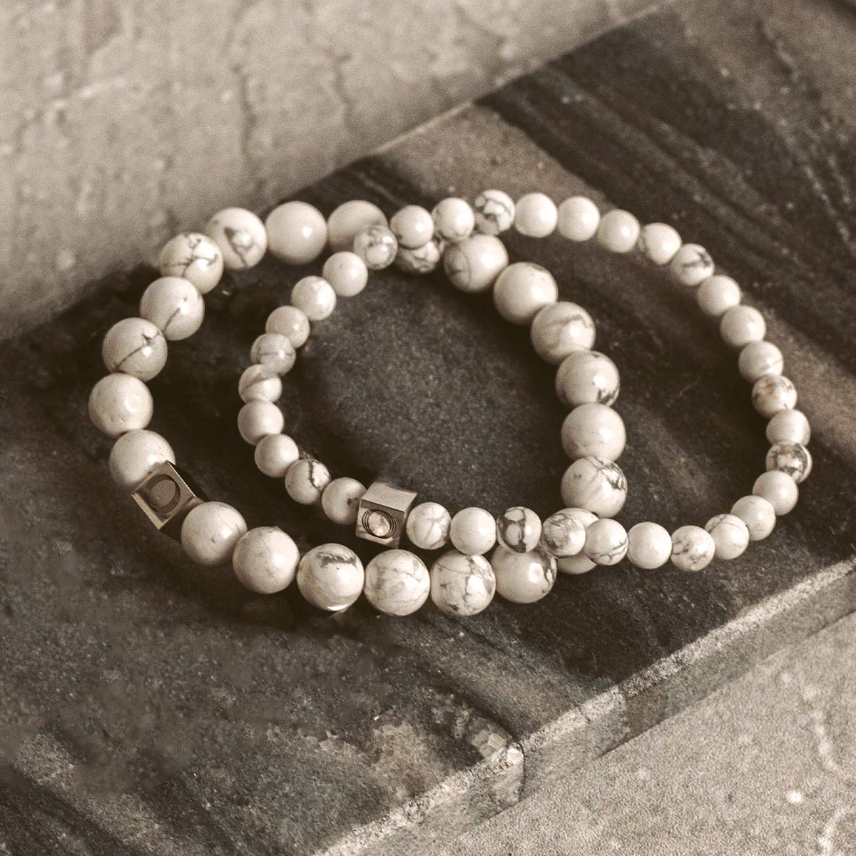Two stone beaded bracelets on a stone slab.