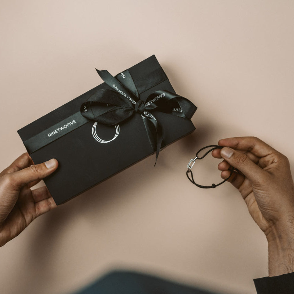 Mann hält eine box für Männer und ein Geschenkarmband für Männer