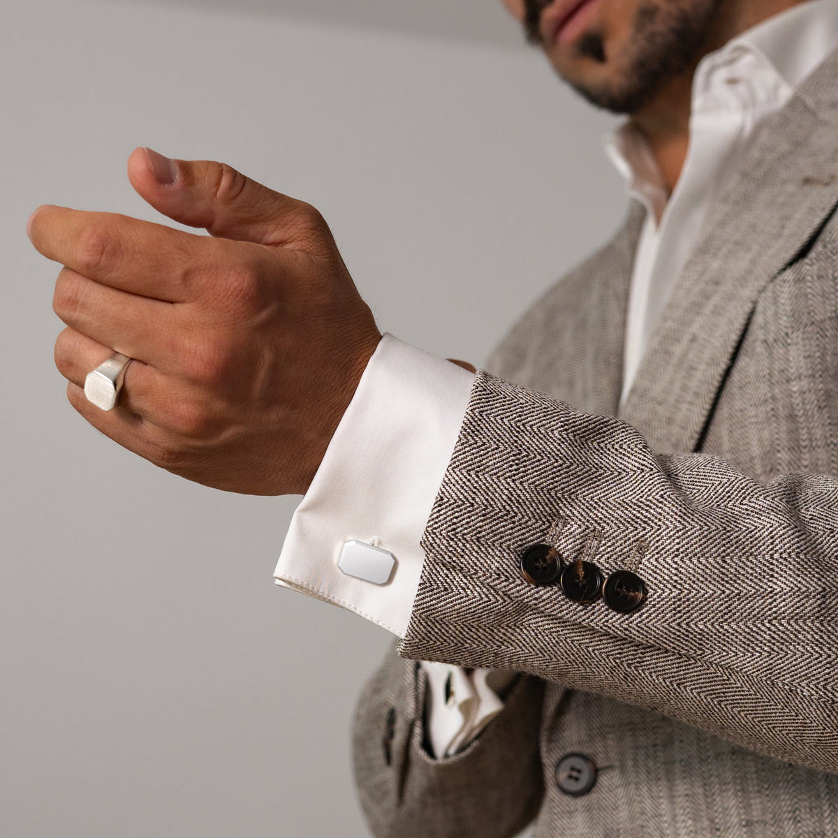Das Model trägt Herrenmanschettenknöpfe und einen Silberring von Ninetwofive.