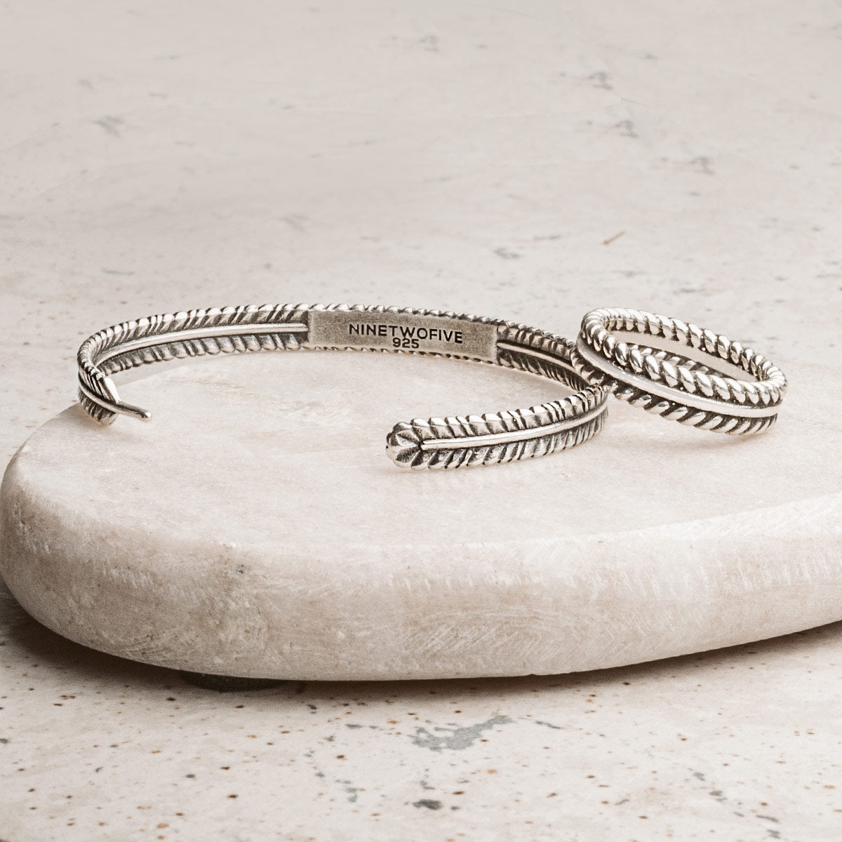 Bracelet et bague en argent 925 présentés sur une pierre blanche. Ninetwofive