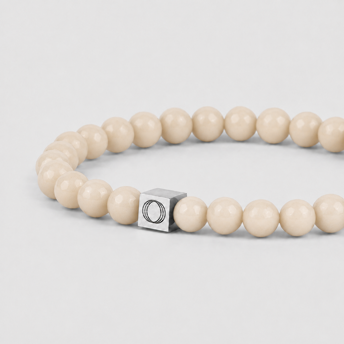 Close-up side angle of the Albij beige mens bracelet, showing the beads and the visible Ninetwofive logo detail.