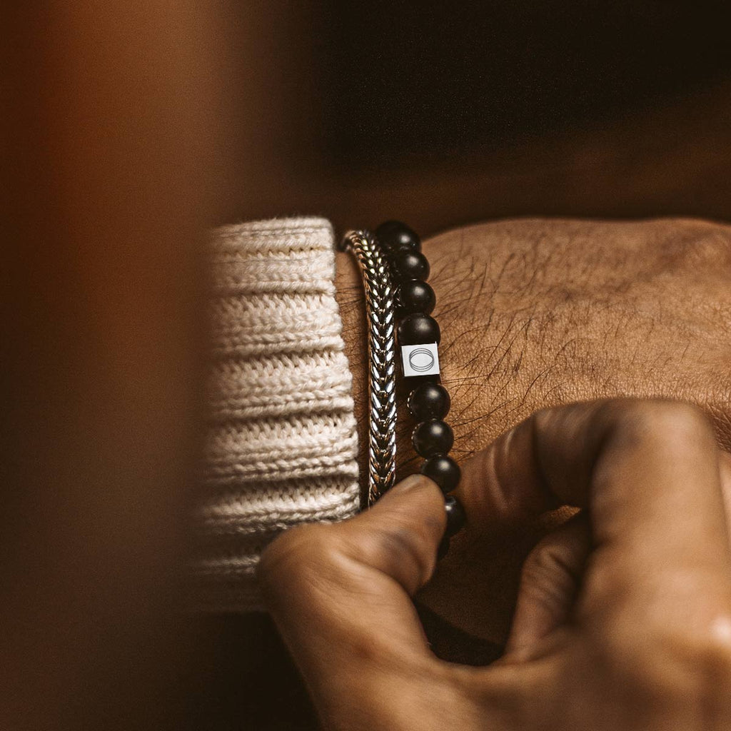 Un homme porte un bracelet Aswad - Matt Black Beaded Bracelet 8mm.