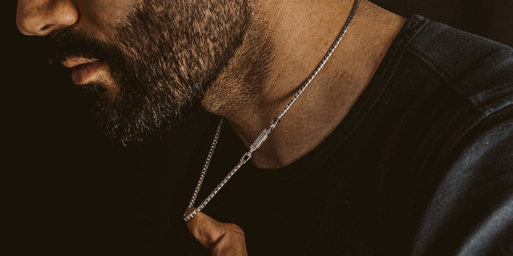 A man with a beard wearing necklace.