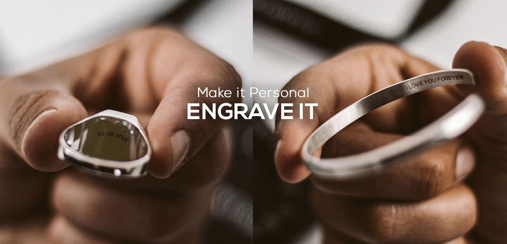 A person is holding a ring with the word engravet on it.