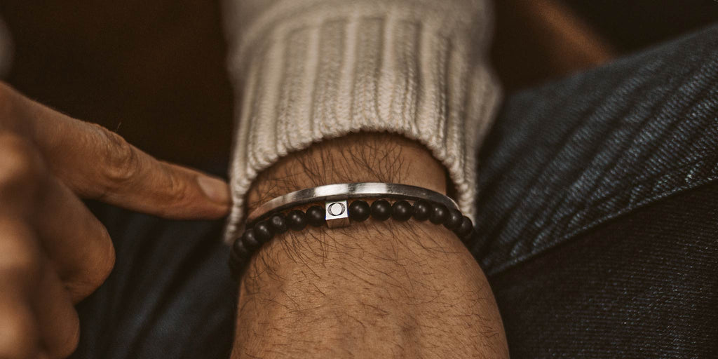 A man wearing a bracelet with a black bead on it.