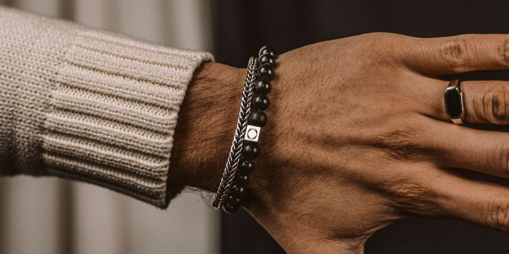 A man's hand with a black bracelet on it.