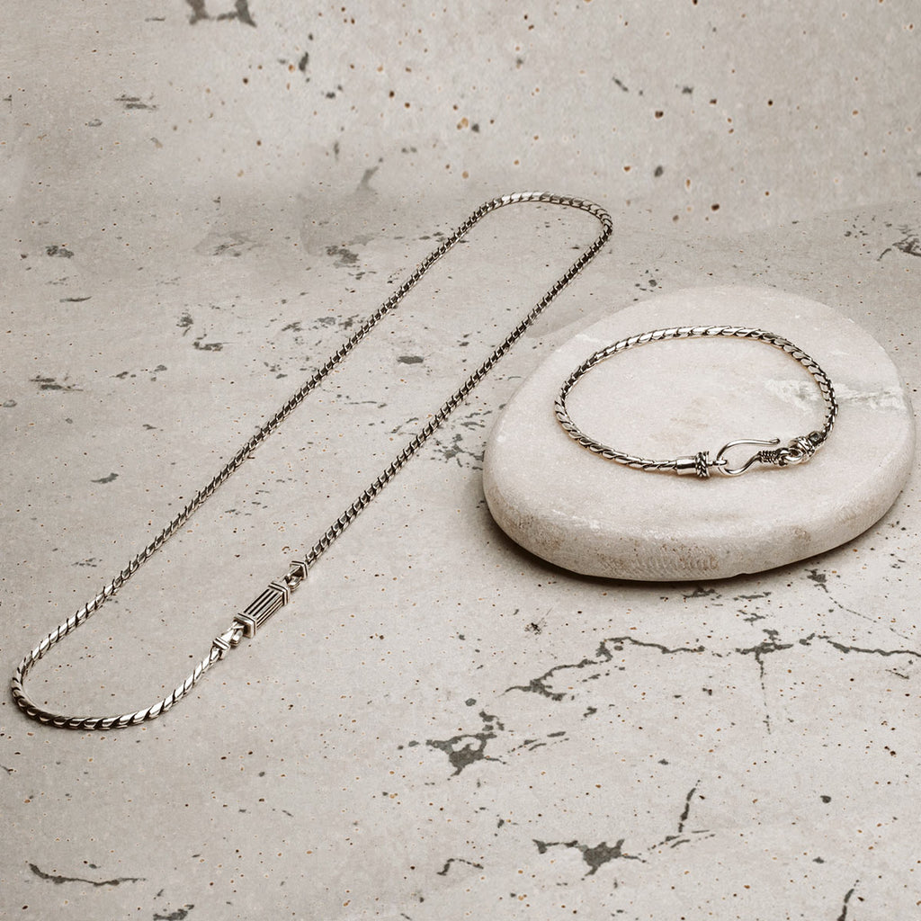 A silver chain and a stone on a table.