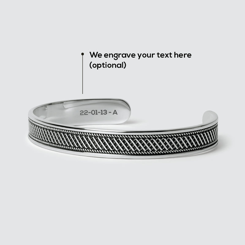 Een Kaliq-armband voor heren van geoxideerd sterlingzilver met een gegraveerde tekst om te laten zien hoeveel ruimte er beschikbaar is voor gratis graveren.