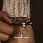 Un homme portant un bracelet Aswad - Matt Black Beaded Bracelet 8mm avec une pierre en onyx.