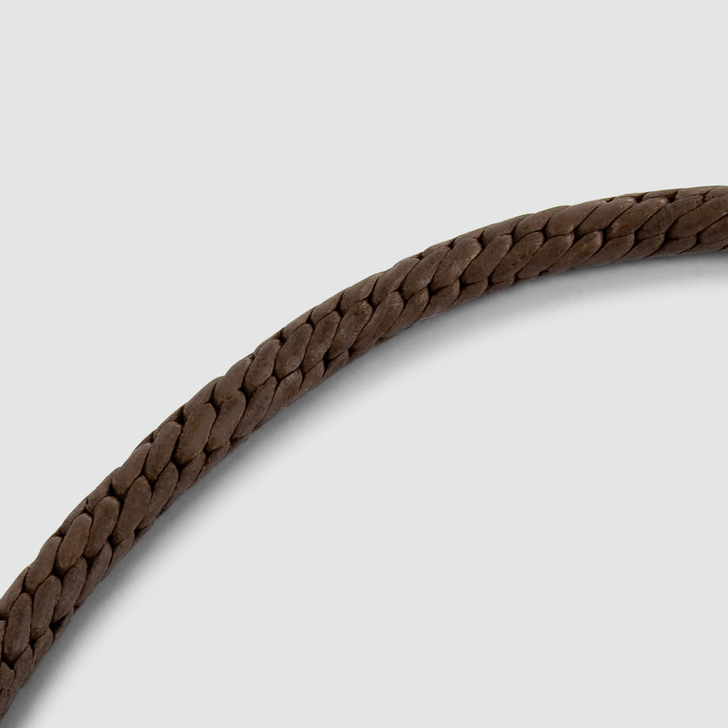 A Taissir - Genuine Brown Leather Bracelet 5mm with an engraved mens bracelet on a white background.