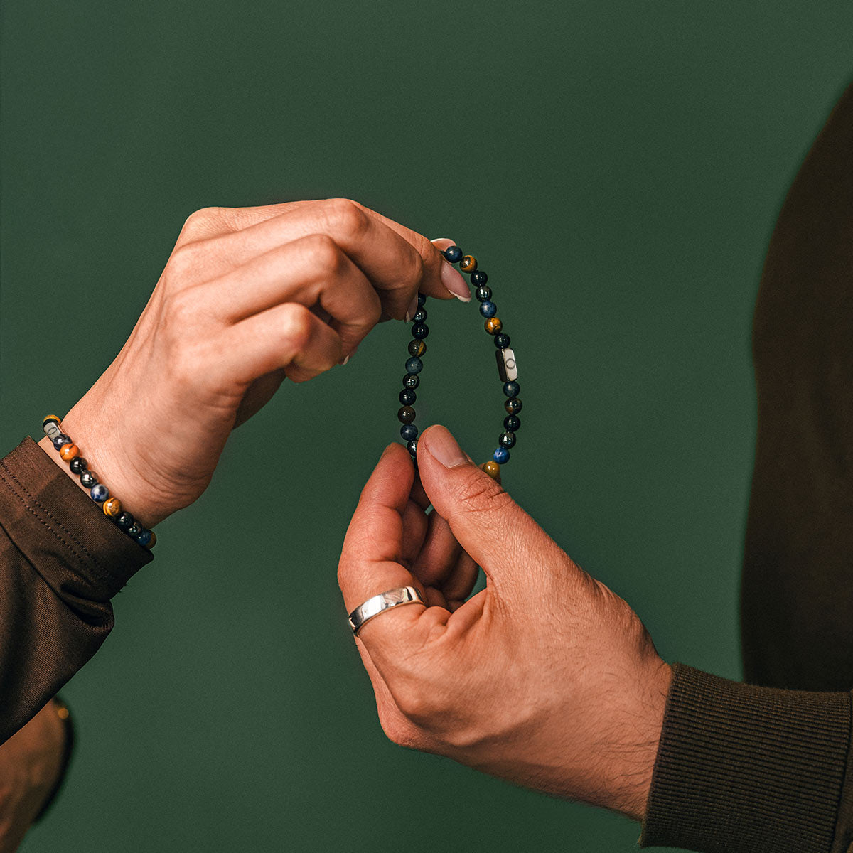 Deux mains tenant un bracelet en perles sur fond vert