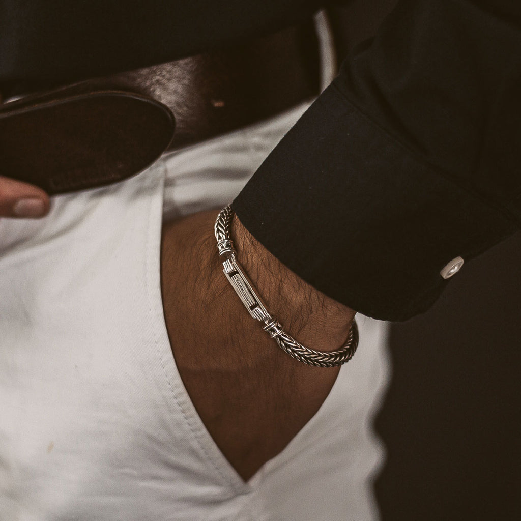 A man wearing a white shirt and a silver bracelet.