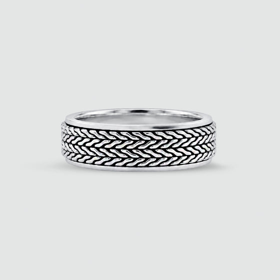 A sterling mens silver ring with a textured, woven basket-like pattern on the outer band, shown on a light gray background. 