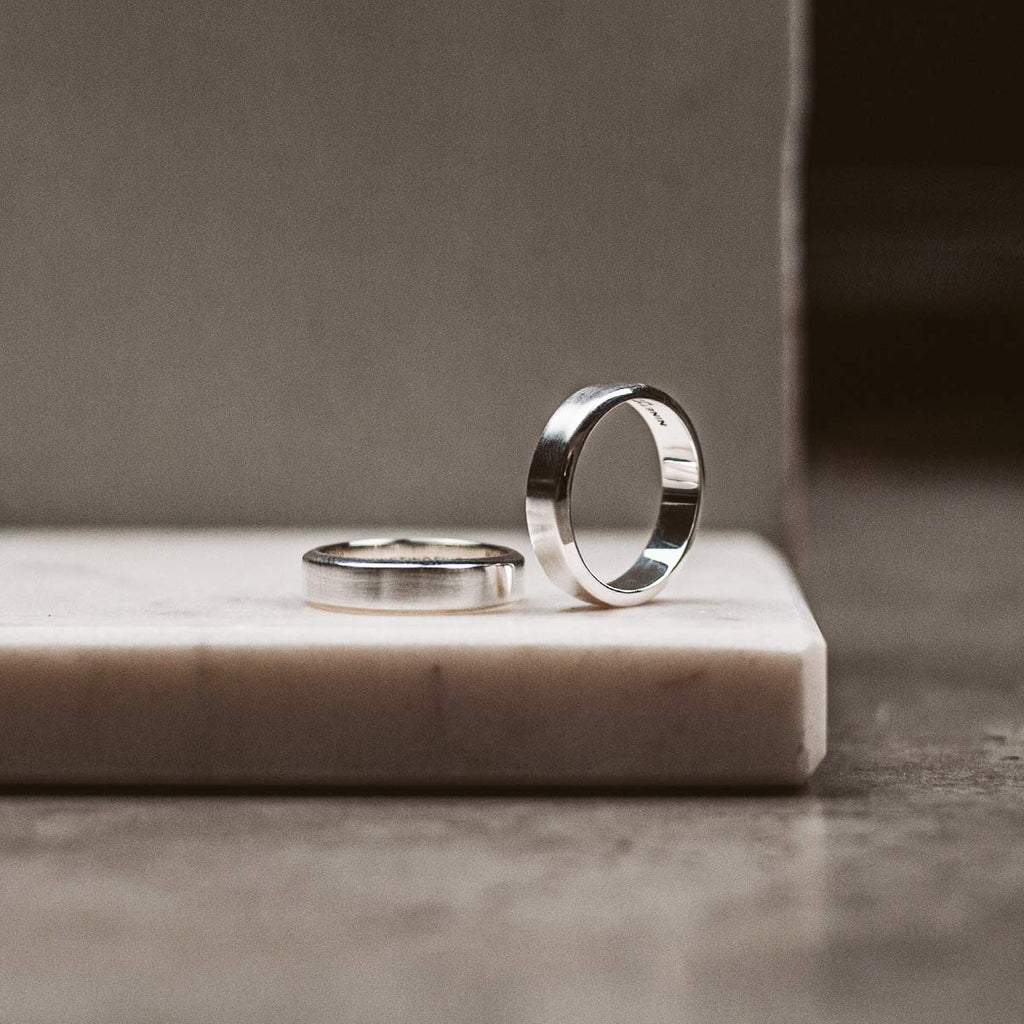 Two silver wedding rings on a marble slab.