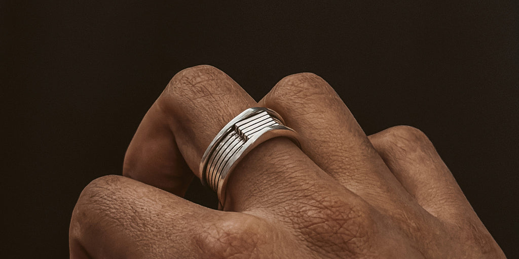 Eine Hand mit einem silbernen Ring an der Hand.