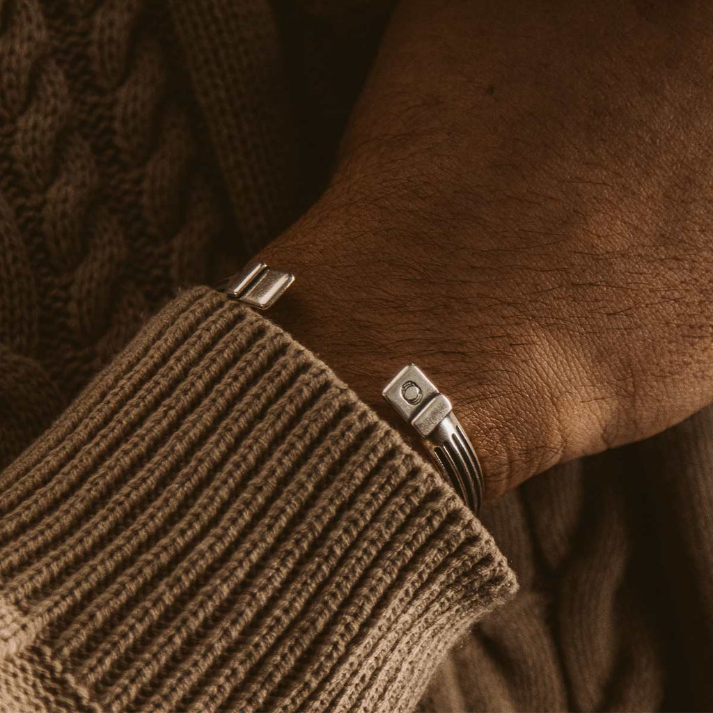 A man wearing a sweater and a silver bracelet.