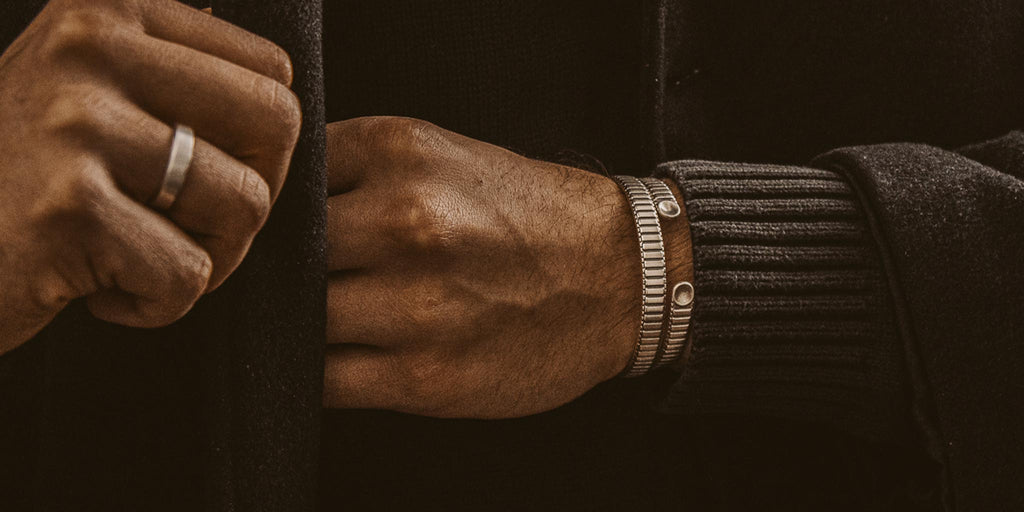Ein Mann trägt ein Paar silberne Armbänder.