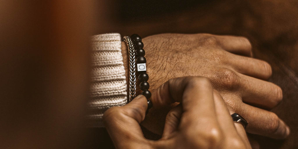 A man is adorning a bracelet.