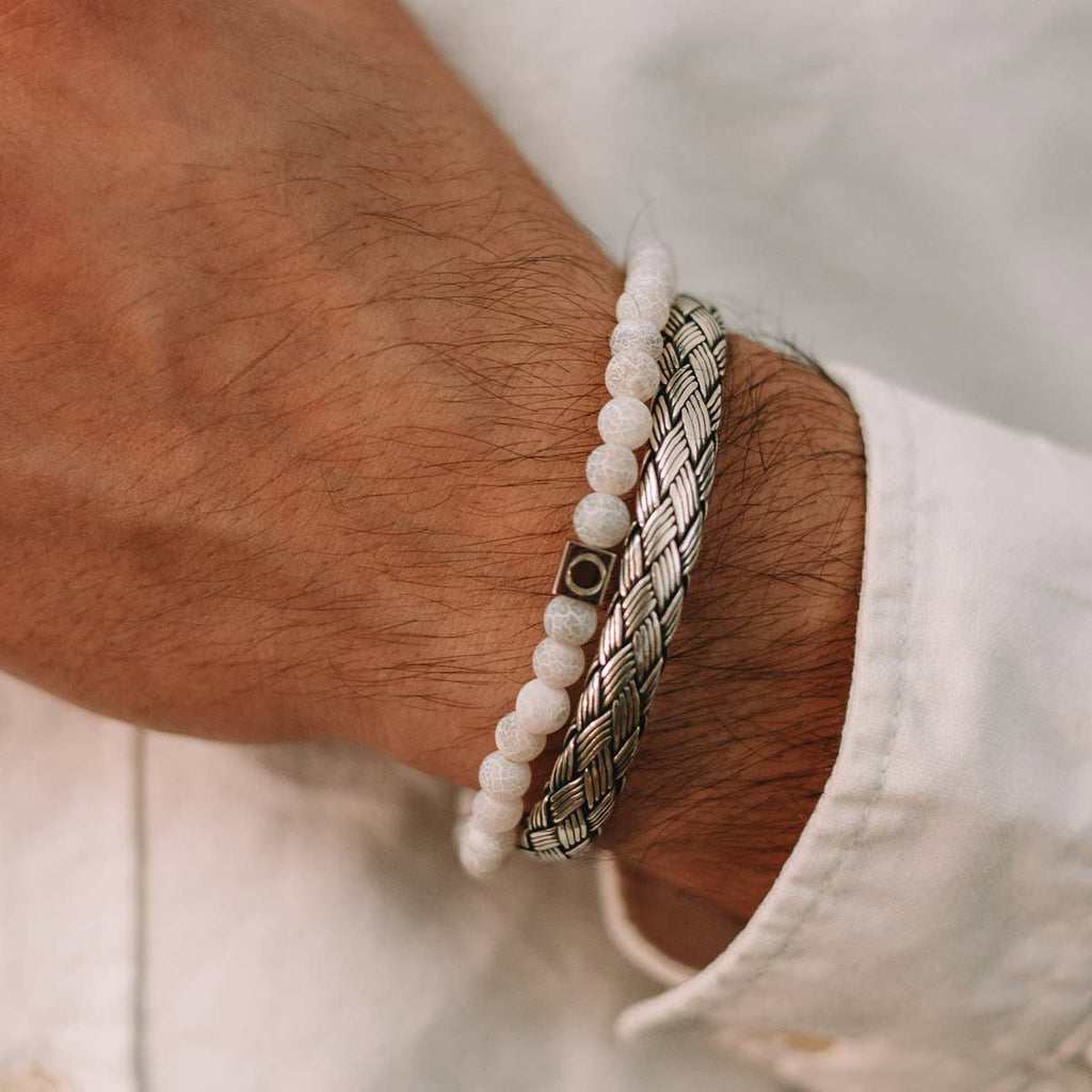 Een man draagt een armband met zilveren kralen.