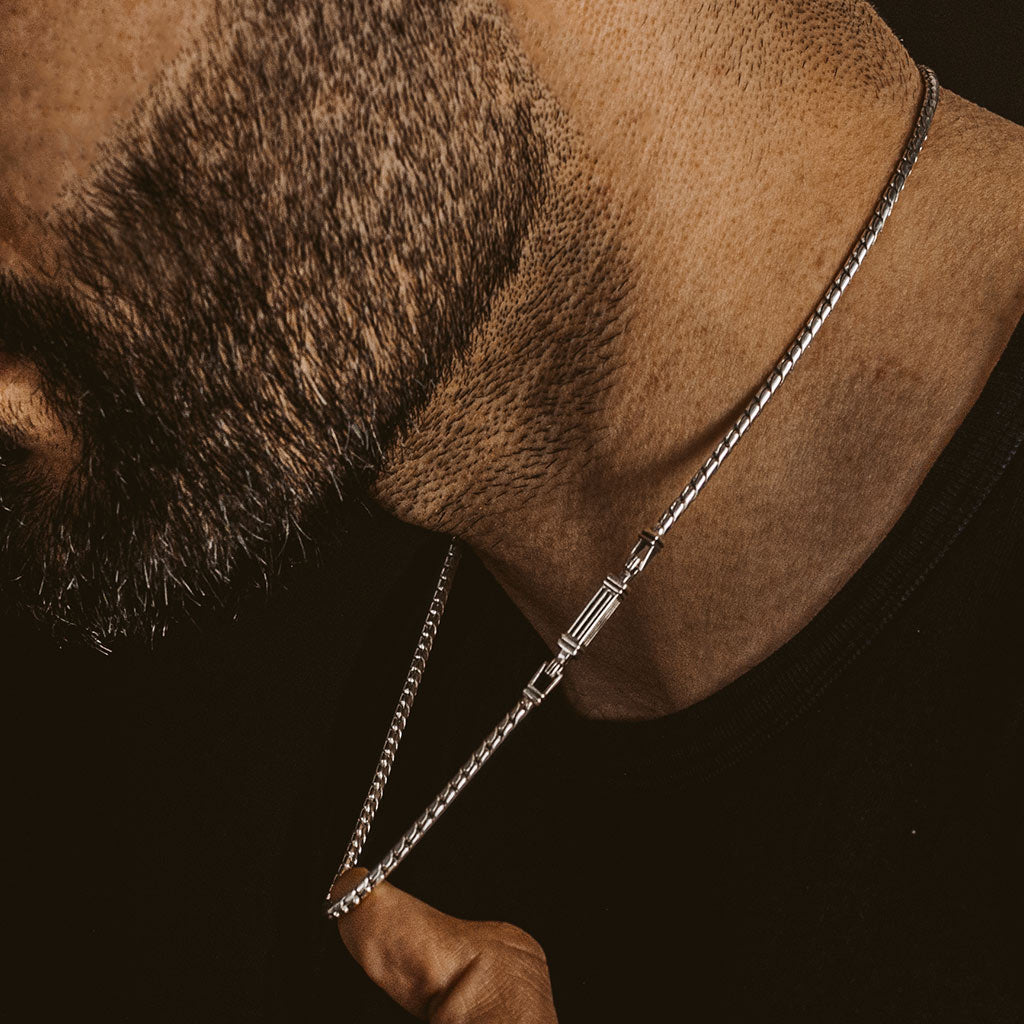 A man wearing a silver chain necklace.