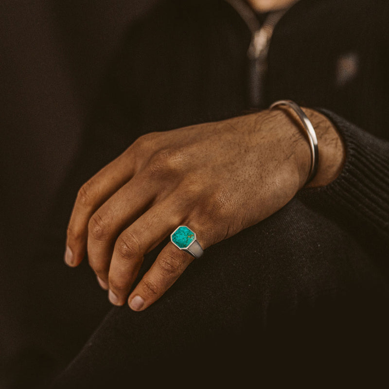 Man rests hand on his knee, showing the Nuri mens ring and a sterling silver bracelet from Ninetwofive.