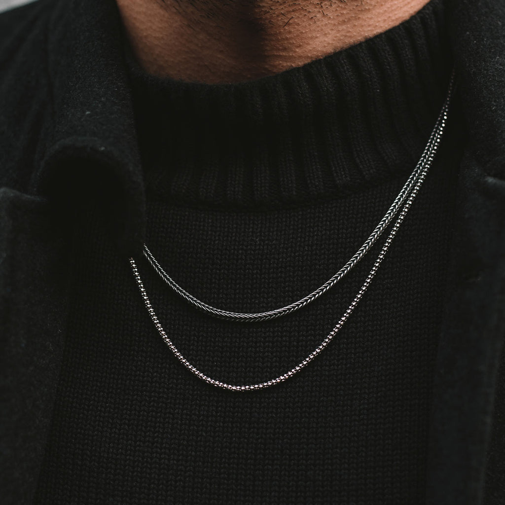 A close up of a man wearing a silver necklace.
