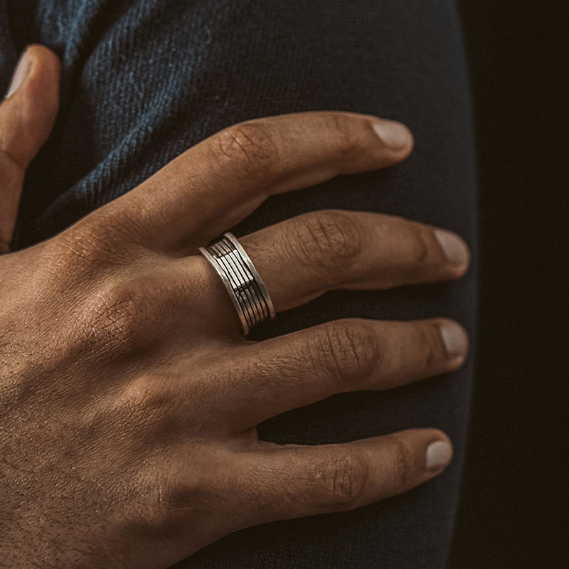 Un homme portant la bague homme Yanel en argent 925 oxydé de Ninetwofive, posant la main derrière l'épaule.