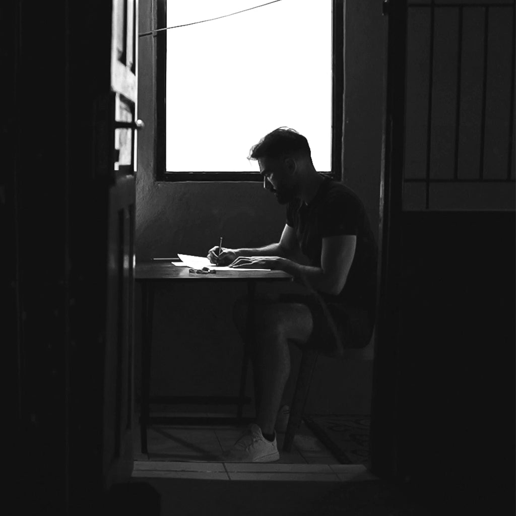 Een man zit aan een bureau voor een raam.