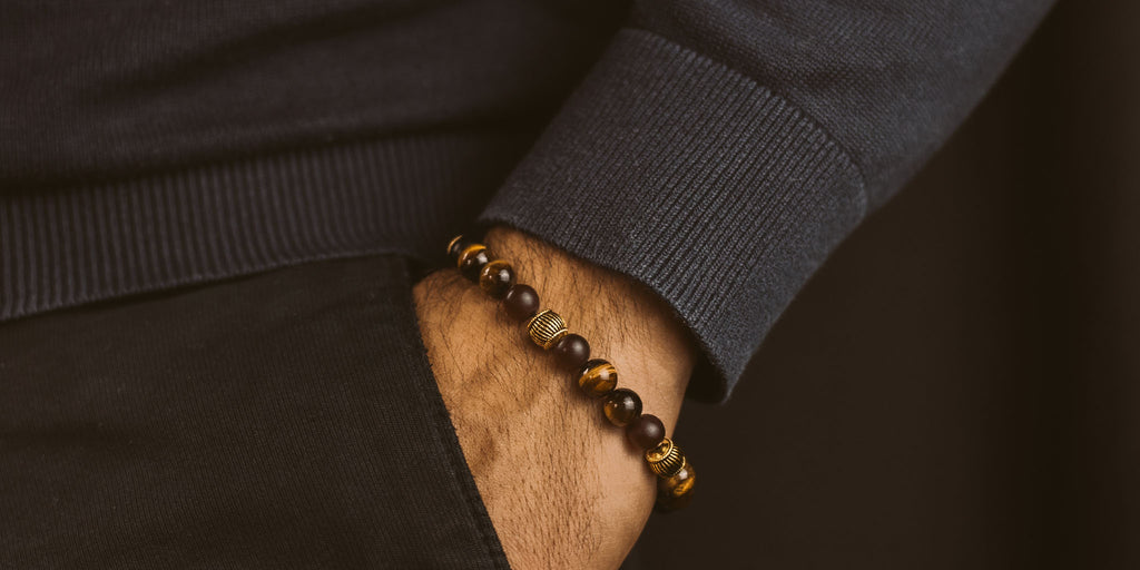 A man wearing a bracelet with tiger eye beads.