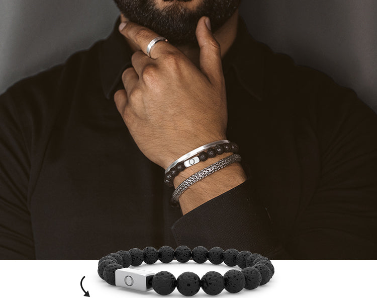 Mann mit schwarzem Hemd und Silberschmuck, der mehrere Armbänder und einen Silberring zeigt - minimalistischer Stil für Männeraccessoires.