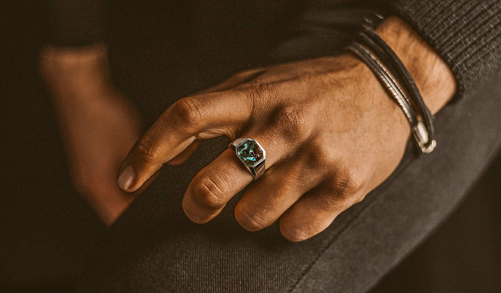Een man met een turquoise ring.