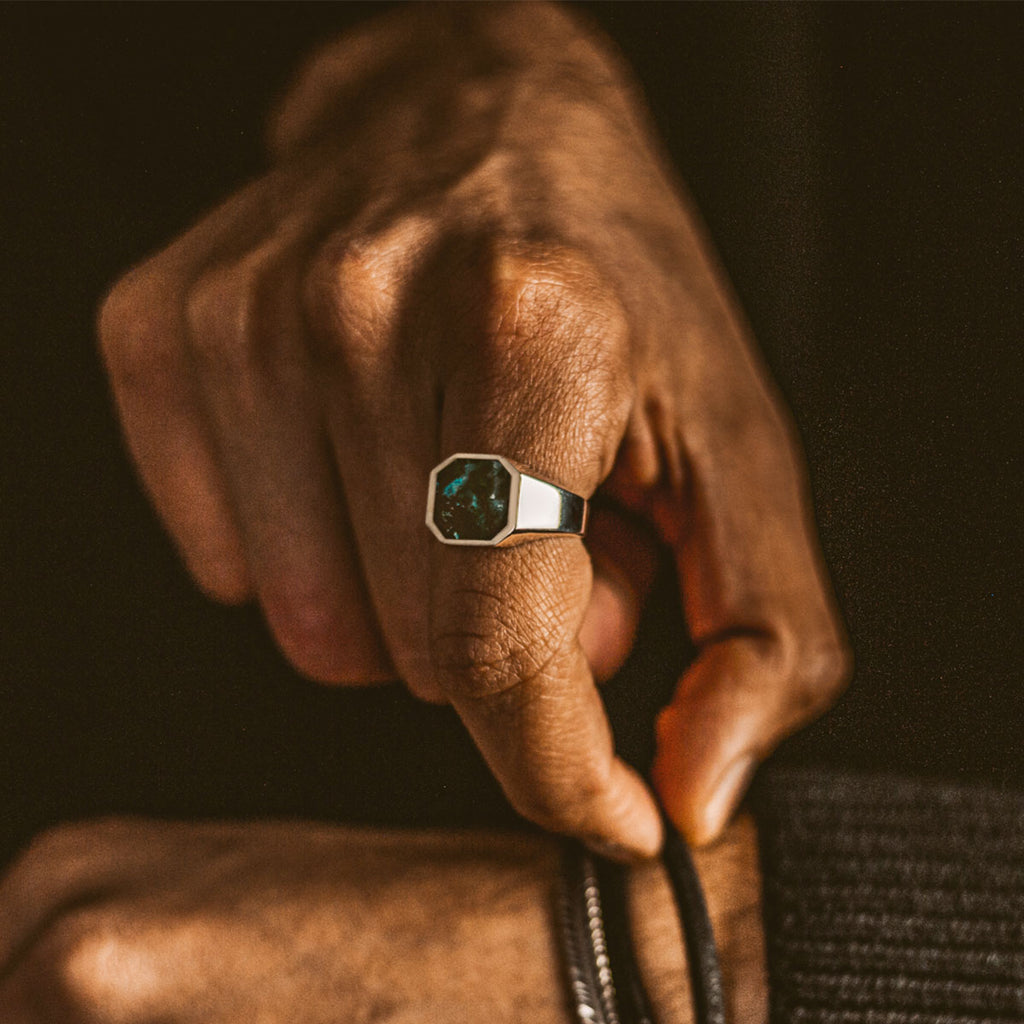 Un homme portant une bague de signet Zaïre - Azurite en argent sterling de 13 mm avec une pierre turquoise .