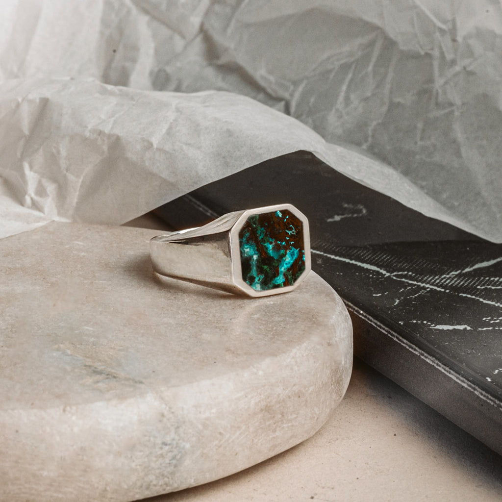 A ring with a turquoise stone on a rock.